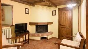 A cozy living room with a fireplace, wooden ceiling, and a television on a stand. - Borgo dei Corsi - VERGAIO 6 Apartment (Raggiolo)