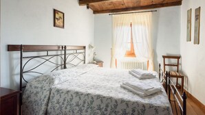 A bedroom with a bed, wooden headboard, and a window with sheer curtains. - Borgo dei Corsi - VERGAIO 6 Apartment (Raggiolo)
