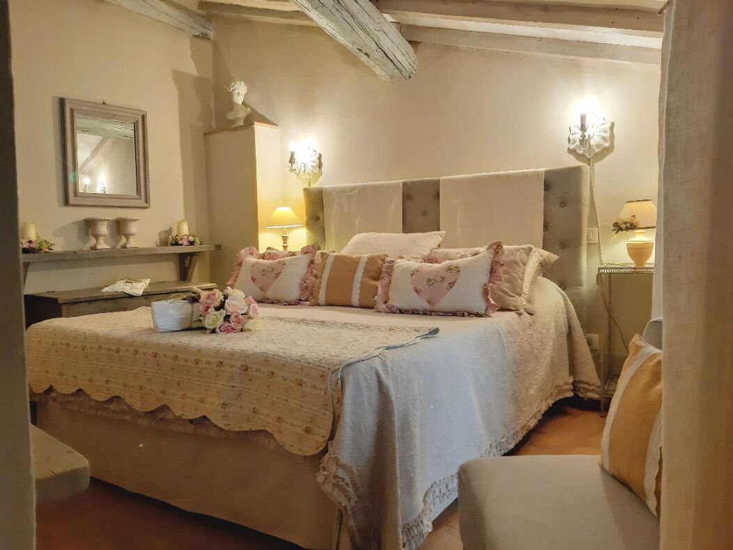 A bedroom with a large bed, bedside tables, a mirror, and a lamp.