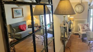 A cozy living room with a mirrored wall, a sofa with a red heart pillow, a lamp, and a clock on the wall. - Cortona Shabby Chic House<br>(Independent & balcony) (Cortona)