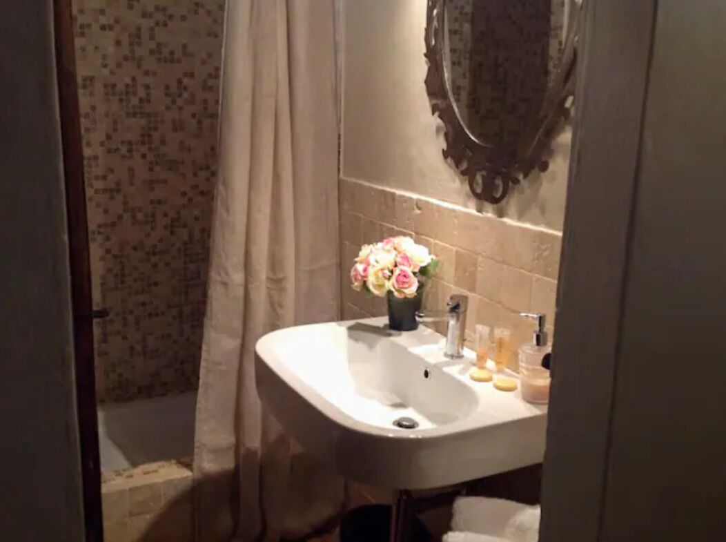 Une salle de bain avec un lavabo blanc, un miroir et un rideau de douche.