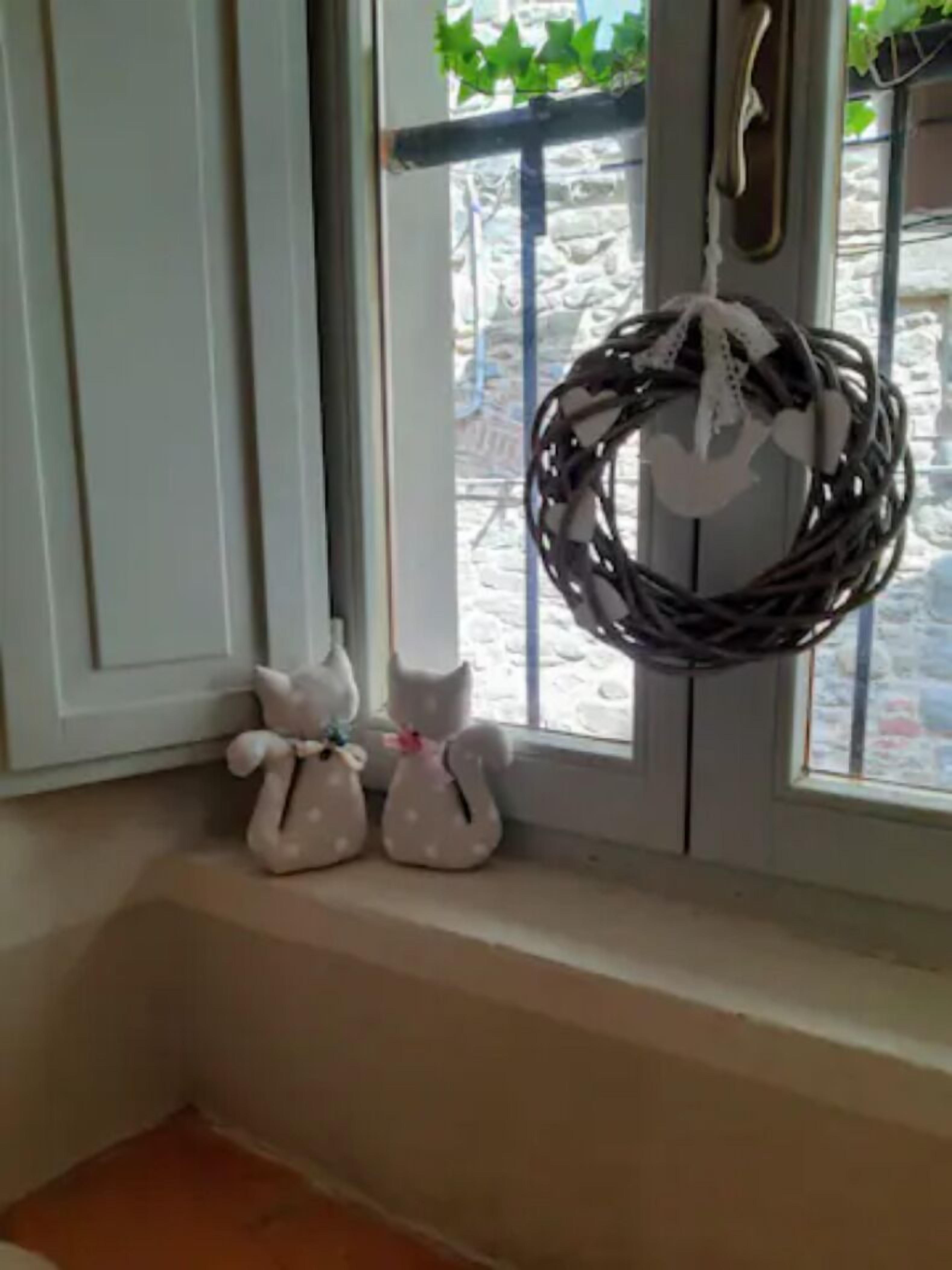 A window with a wicker basket and two white cat-shaped decorations on the sill.