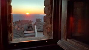 A window view of a town at sunset with buildings and a clear sky. - Cortonas Rooftop Nest (Cortona)