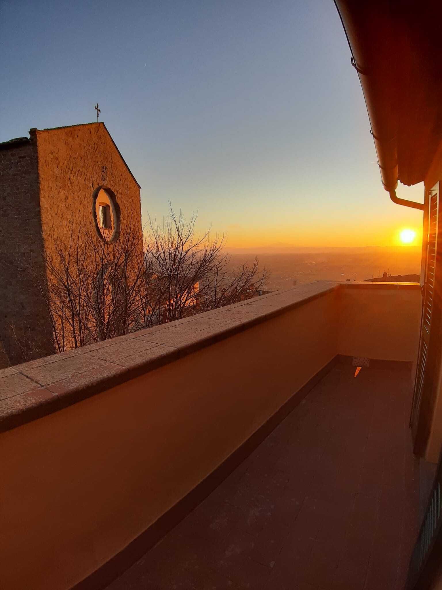 A balcony with a view of a sunset over a cityscape.