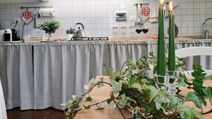 A kitchen with a gas stove, a kettle, and a table with a plant and candles. - Cortonas Rooftop Nest (Cortona)