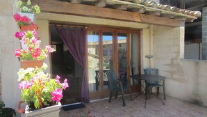 Un espace patio aménagé avec une table et des chaises, une porte-fenêtre coulissante et des plantes en pot.