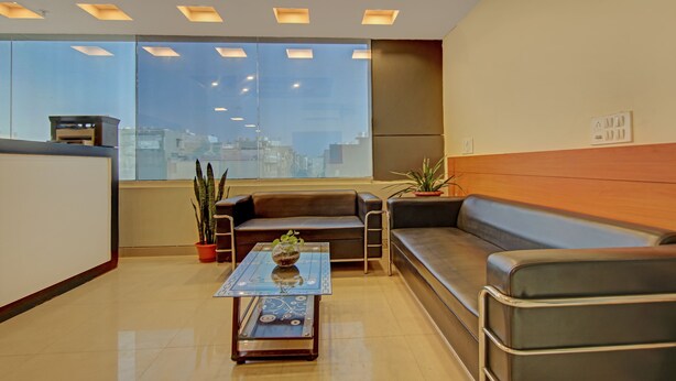 A modern waiting area with leather sofas, a glass coffee table, and potted plants. - Treebo TMS Residency (New Delhi)