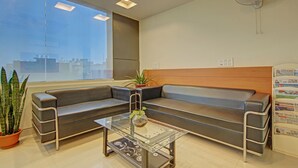 A modern waiting area with a glass-top table, a leather sofa, and a potted plant. - Treebo TMS Residency (New Delhi)