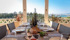 Une table dressée pour le repas, avec des bouteilles de vin, du fromage, du pain et des olives.