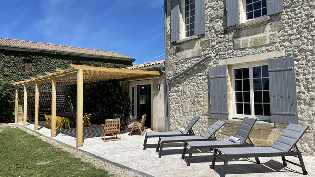 A stone building with a covered patio area featuring outdoor furniture and a pergola. - A quaint vineyard gîte at Château Magdeleine Bouhou (Cars)