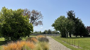 A landscaped garden with a gravel path, various shrubs, and trees. - A quaint vineyard gîte at Château Magdeleine Bouhou (Cars)