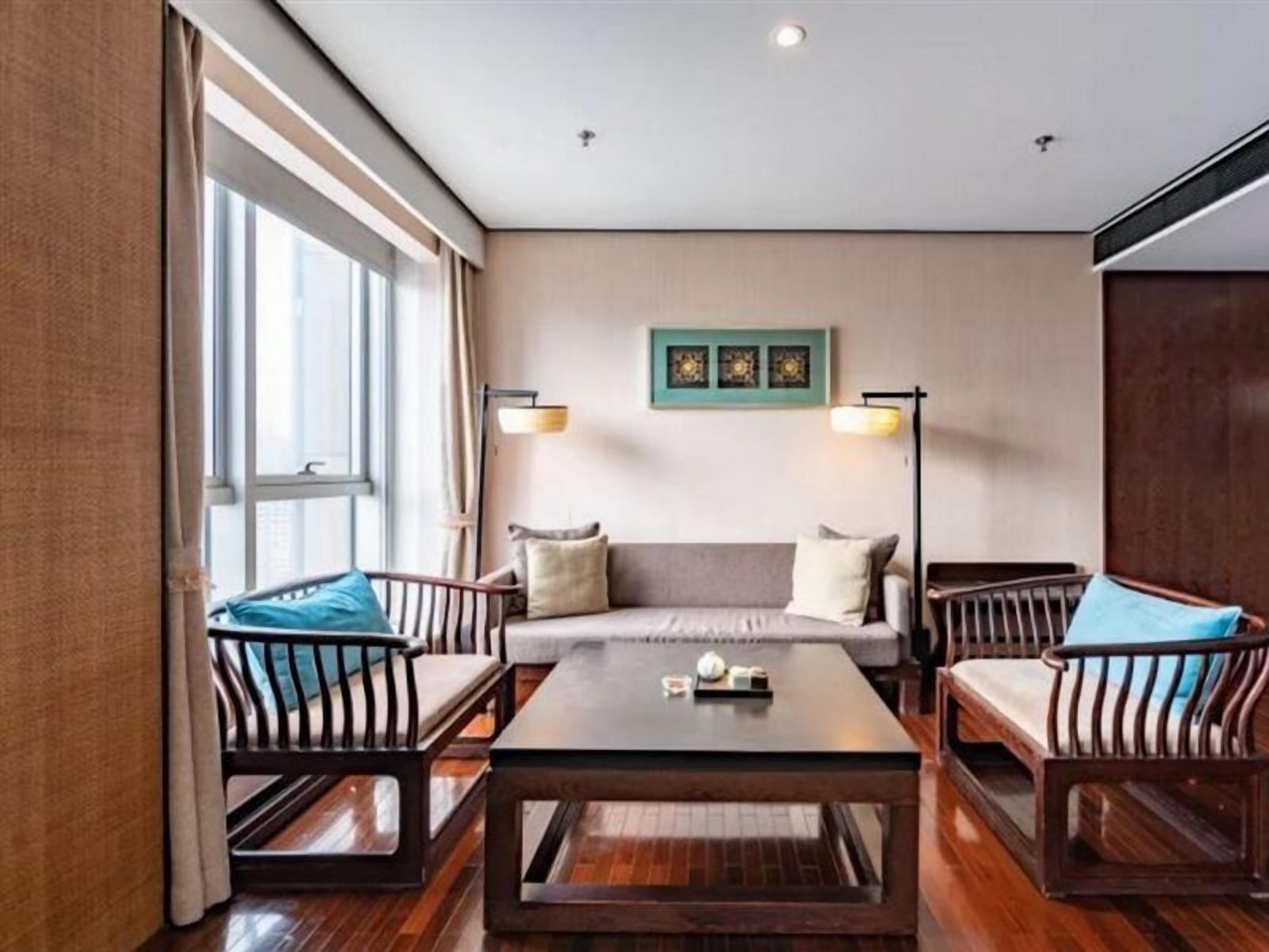 A room with a sofa, two armchairs, a coffee table, and a floor lamp.