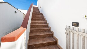 A staircase with brown tiles, white walls, and a red handrail. - Villetta Roberta - Primo Piano by BarbarHouse (Santa Maria al Bagno)