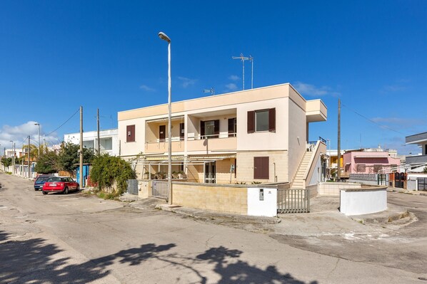 A two-story building with a balcony, a staircase, and a parked car. - Carlotta`s House by BarbarHouse (San Foca)