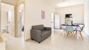 A compact living space with a sofa, dining table, chairs, and a refrigerator. - Carlotta`s House by BarbarHouse (San Foca)