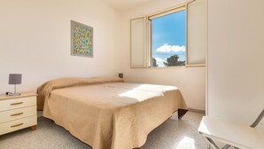 A bedroom with a bed, a desk, a chair, a window with a view, and a framed picture on the wall. - Carlotta`s House by BarbarHouse (San Foca)