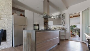 Une cuisine moderne dotée d’un îlot central, d’appareils électroménagers intégrés et offrant une vue sur l’espace extérieur.