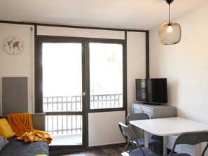 A room with a bed, a table with chairs, a television, and a sliding door to the outside.