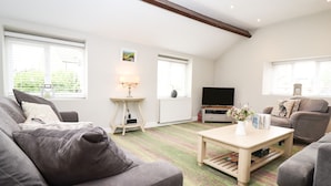 Ein Wohnzimmer mit Sofa, Couchtisch, Fernseher und Lampe.