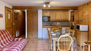 Eine kompakte Küche mit Holzausstattung, einer Mikrowelle und einem Essbereich mit Tisch und Stühlen.