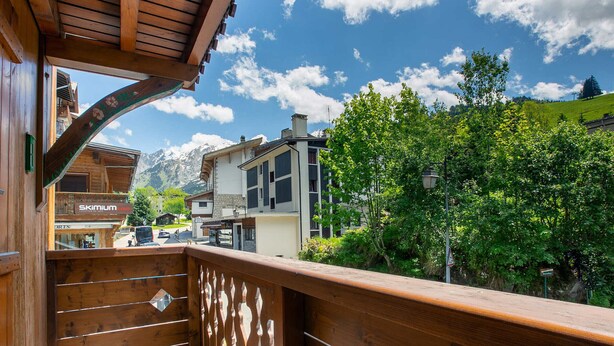 Ein Holzbalkon mit Blick auf einen Berg, ein Skigebiet und ein Restaurant namens "Skimium".