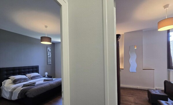 A bedroom with a bed, bedside tables, a wall-mounted lamp, and a door with a unique design.