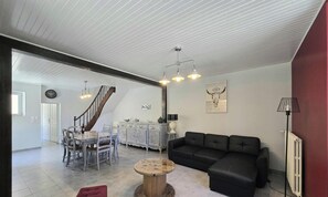A spacious living area with a staircase, a dining table with chairs, a black leather sofa, and a round coffee table.