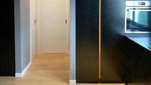 A modern kitchen with a black refrigerator, wooden flooring, and a white door in the background. - LeMummarelle36Apartment (Naples)