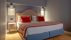 A neatly made bed with red and white bedding, a round bedside table, and wall-mounted lights. - LeMummarelle36Apartment (Naples)