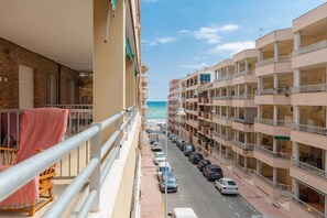 Un immeuble à plusieurs étages doté de balcons, situé devant une rue et offrant une vue sur la mer.