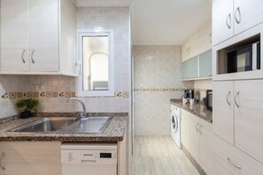Une cuisine moderne équipée d’un lave-vaisselle encastré, d’un évier avec un robinet et d’un four à micro-ondes.