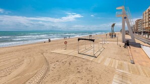 A beach with a wooden boardwalk, a lifebuoy, and a modern structure with a spiral staircase. - Fidalsa Bay View Romance (Guardamar)
