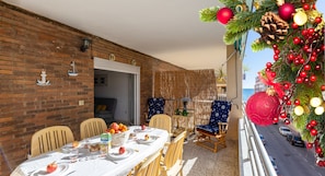 A dining area with a brick wall, a table set for two, and a Christmas tree with ornaments. - Fidalsa Bay View Romance (Guardamar)
