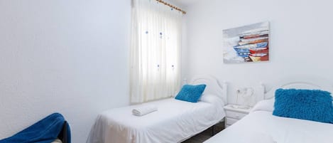Une chambre d’hôtel avec deux lits, une fenêtre avec des rideaux, une table de chevet, une commode et un tableau au mur.