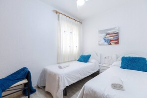 Une chambre d’hôtel avec deux lits, une fenêtre avec des rideaux, une table de chevet, une commode et un tableau au mur.