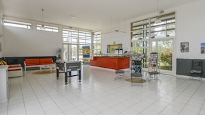 Una habitación amplia con una recepción, una mesa de fútbol de mesa y un sofá.