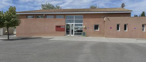A building with a tiled roof, a glass entrance, and a red mailbox.