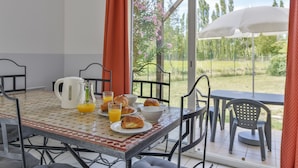 Una mesa de desayuno con croissants, zumo de naranja y una cafetera.