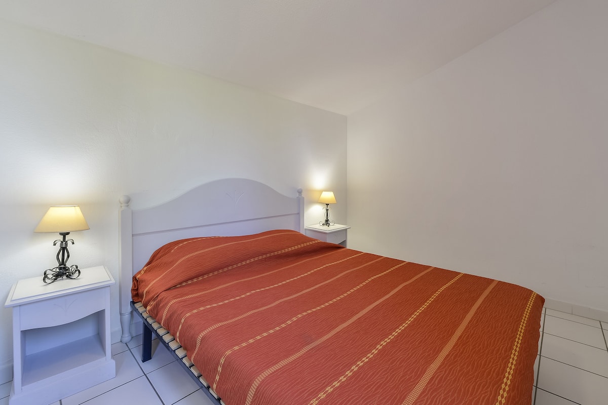 Een slaapkamer met een bed, twee nachtkastjes met lampen en een wit plafond.