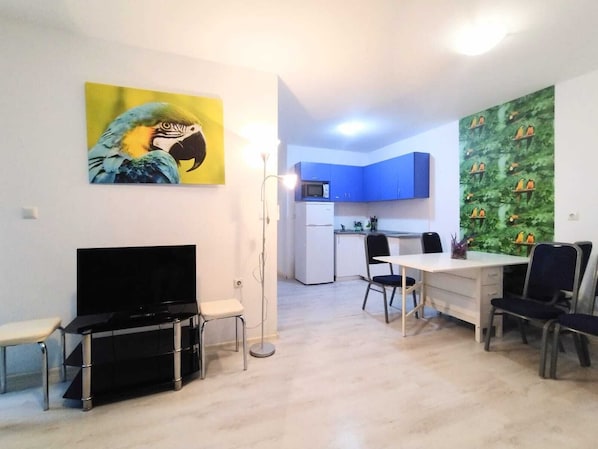 A compact living space with a dining area, kitchenette, and a large painting on the wall.