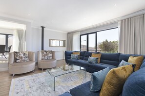 A modern living room with a sectional sofa, a glass coffee table, and a patterned rug. - Villa Balmoral 14 (Cape Town)