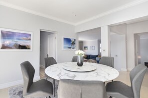 A modern dining area with a marble table, grey upholstered chairs, and a vase of white flowers. - Villa Balmoral 14 (Cape Town)