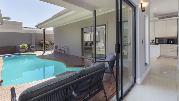 A modern house with a swimming pool, a patio with outdoor furniture, and a kitchen area. - Villa Balmoral 14 (Cape Town)