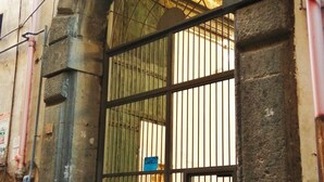 Une entrée fermée par une grille métallique, un panneau bleu et un panneau indiquant qu’il est interdit de se garer.