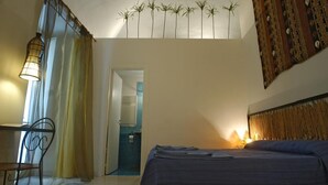 Une chambre à coucher comprenant un lit, une chaise, un bureau et un mur orné d’une tapisserie à motifs.
