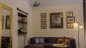 Un salon avec un canapé de couleur sombre, une petite table ronde sur laquelle se trouvent une tasse et une soucoupe, un lampadaire et un grand miroir.