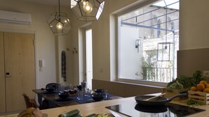 Una cocina moderna con un ventanal grande, una tabla de madera con verduras, una sartén y una estufa empotrada.