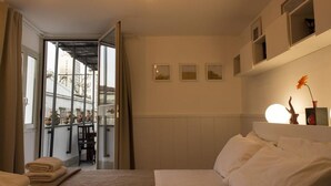 A hotel room with a bed, a desk, and a view of the city through large windows. - Sui Tetti di Napoli - panoramic terrace 3 (Napoli)