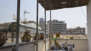 A rooftop terrace with a table set for dining, surrounded by potted plants and a view of the cityscape. - Sui Tetti di Napoli - panoramic terrace 3 (Napoli)