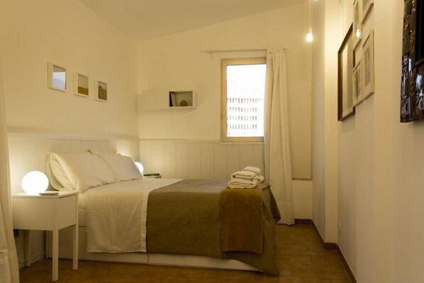 Une chambre à coucher avec un lit, une table de chevet et une fenêtre avec des rideaux.